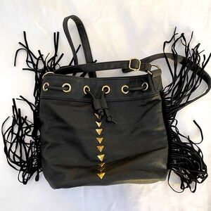 Black faux leather bucket handbag with gold triangle details, tassels.